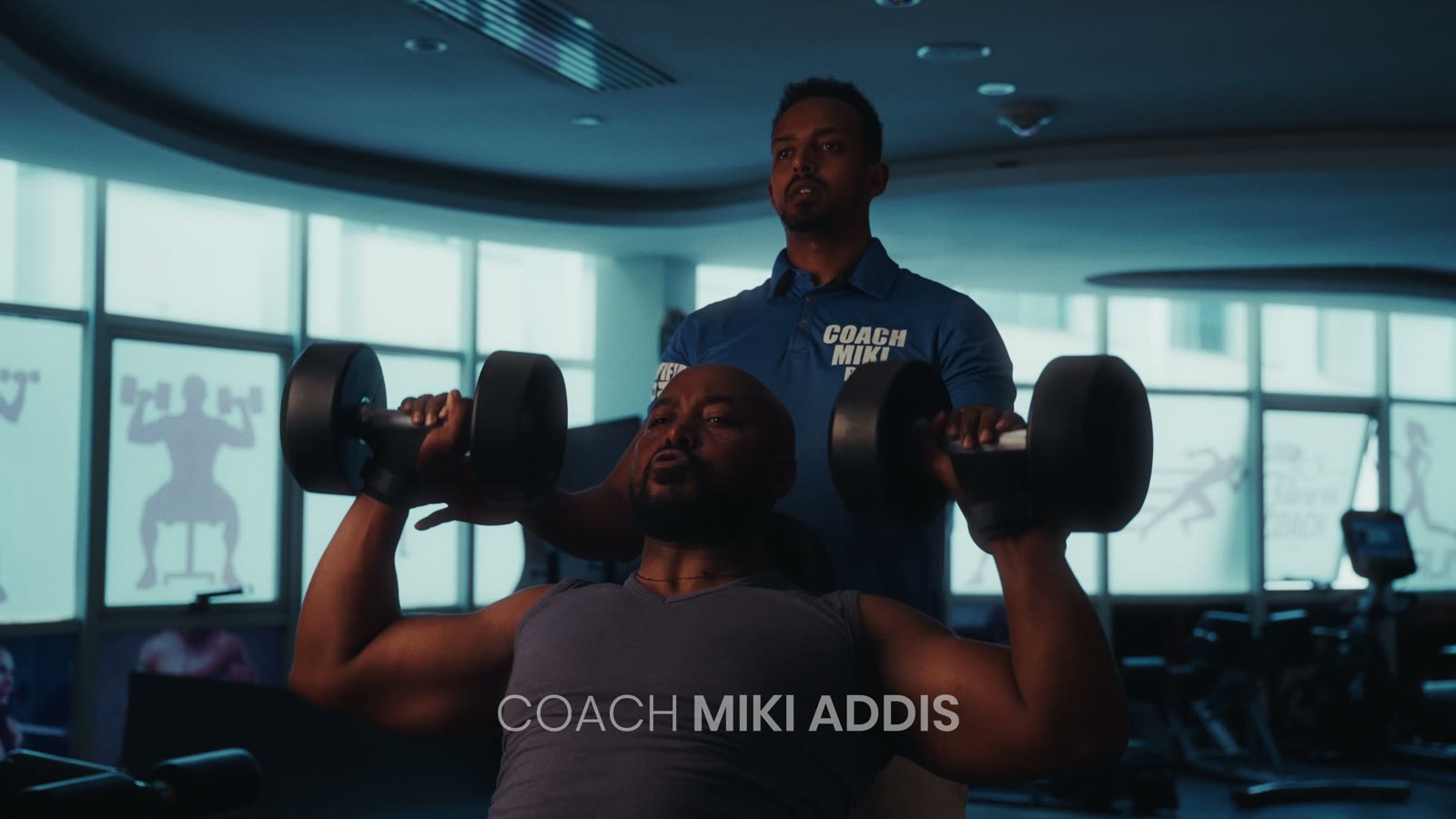 Coach Miki spotting a client's dumbbell shoulder press